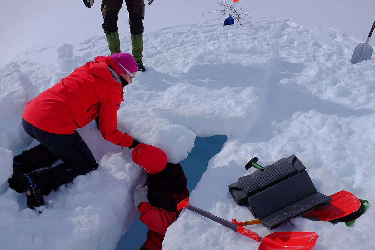 A person cutting and stacking blocks of packed snow