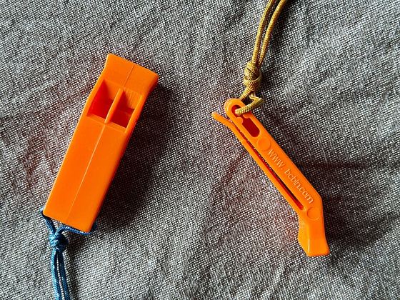 Two bright orange emergency whistles on a cord
