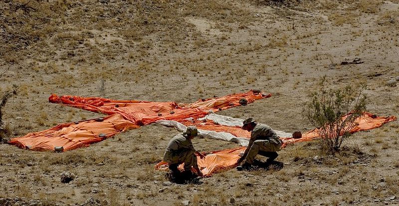 Bright orange cloth laid out in a large X on an open hillside