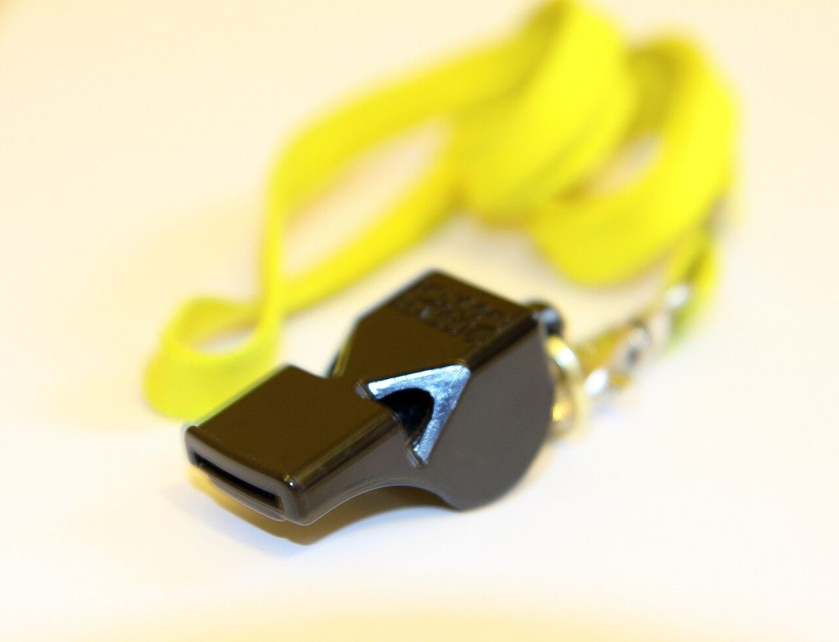 A black pealess whistle on a yellow lanyard