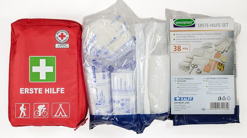 A red first aid kit with bandages laid out beside it