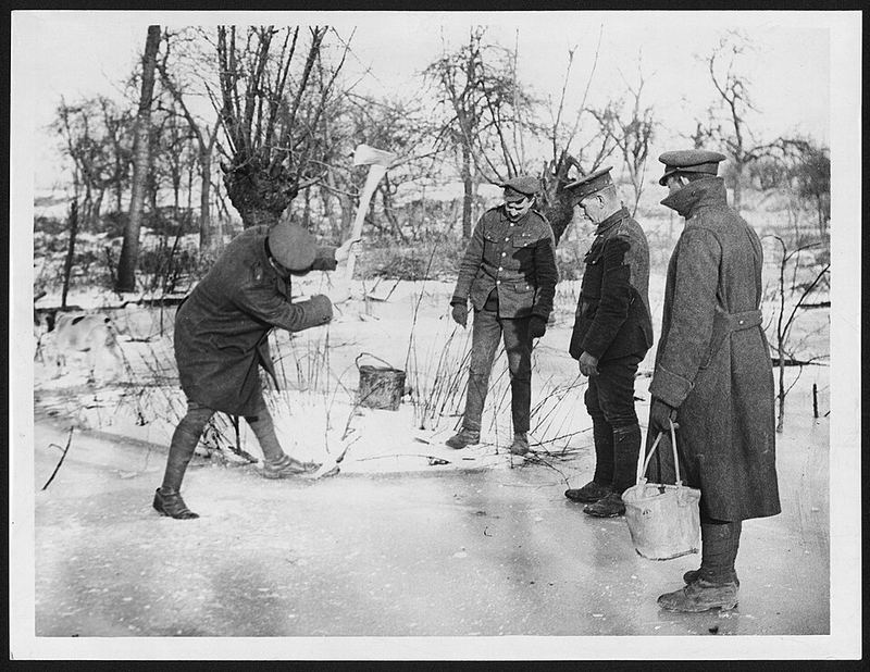 A soldier swings an axe at ice while others wait with buckets
