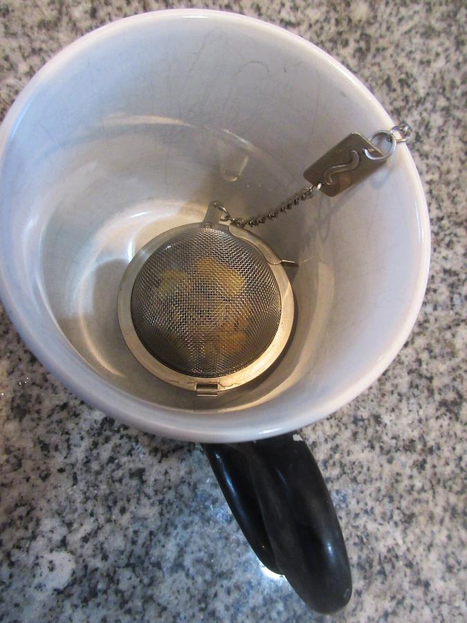 Crushed acorn pieces in a tea ball soaking in a mug of water